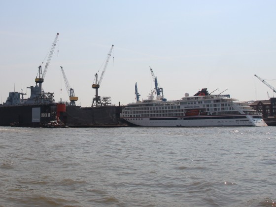 Winziges Kreuzfahrtschiff und Fregatte in Dock 11