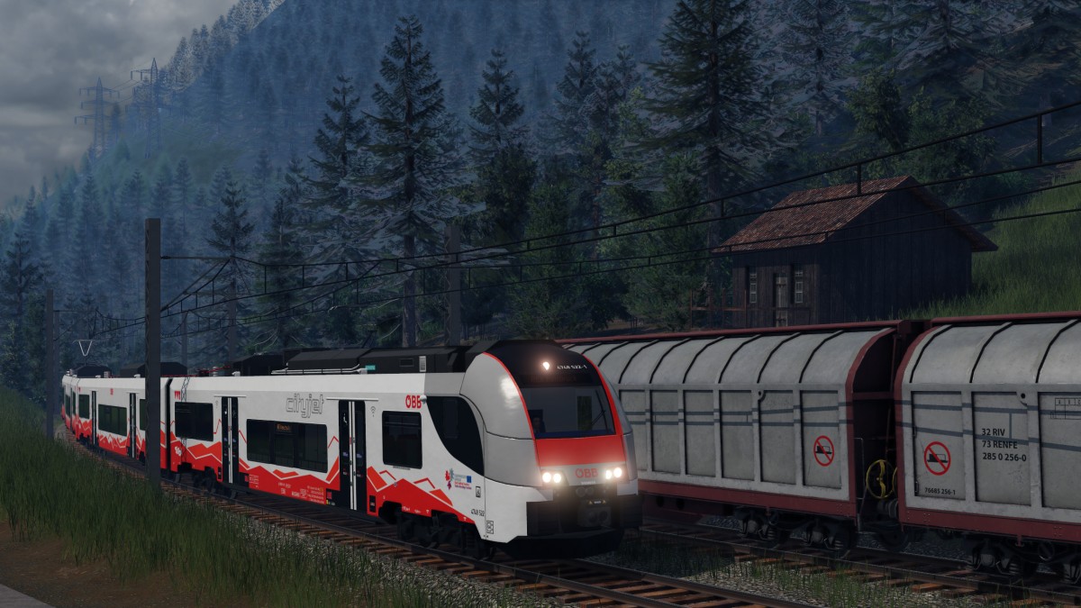 Tiroler Cityjet wartet auf Vorbeifahrt des kreuzenden Güterzug