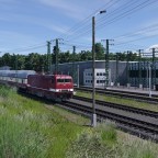 Eine BR 243 fährt mit ihrem Doppelstockzug am Bahnstromwerk vorbei.